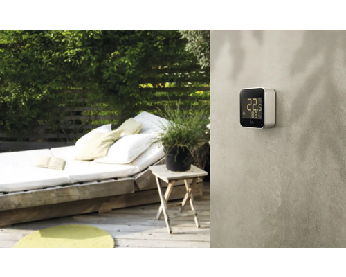 Szene im Garten mit digitalem Thermometer an der Wand.
