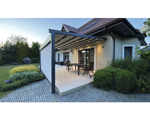 Terrasse mit Pergola, Tisch und Stühlen an einem Haus.