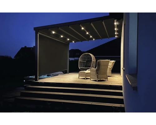 Beleuchtete Terrassenüberdachung mit Sitzgelegenheiten auf Holzterrasse bei Nacht