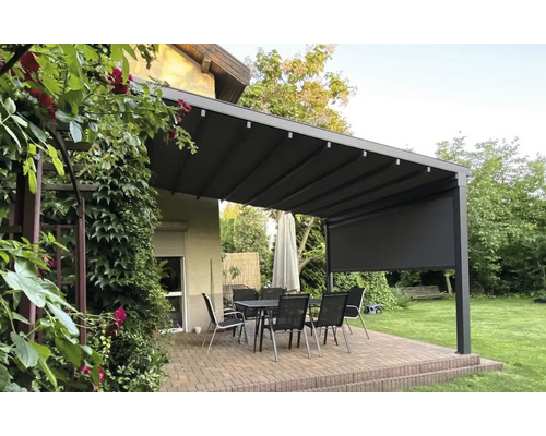 Pergola mit Markise, Tisch und Stühlen im Garten.