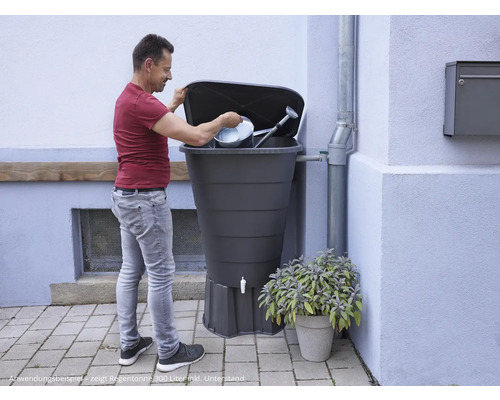 Mann befüllt Regentonne mit Gießkanne