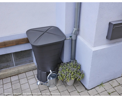 Regentonne mit Regensammler, Gießkanne und Bepflanzung vor Hauswand