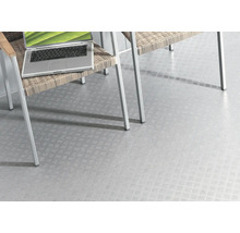 Heller Bodenbelag mit Riffelblechmuster unter einem Stuhl und einem Laptop.