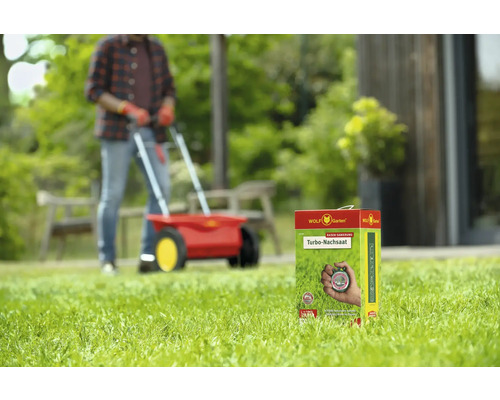 Wolf Garten Turbo Nachsaat Packung vor einem Mann mit Streuwagen auf einem Rasen