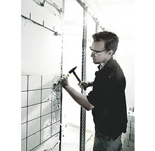 Ein Mann schlägt mit einem Hammer und einem Meißel Fliesen von einer Wand ab.