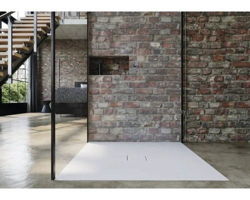 Moderne Dusche mit flacher Duschwanne und Glasabtrennung vor einer Ziegelwand.