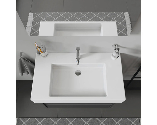 Aufsicht eines weißen Waschbeckens mit Armatur, Seifenspender und Zahnbürstenhalter im Badezimmer