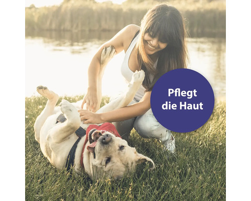 Frau spielt mit Hund im Gras: Pflegt die Haut