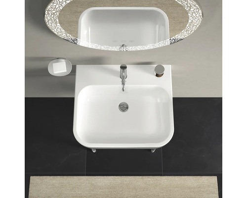 Ansicht von oben Waschbecken mit Armatur, Seifenschale und beleuchtetem Spiegel in einem Badezimmer.