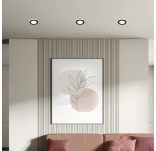 Ansicht eines Wohnzimmers mit Deckeneinbaustrahlern, Wandpaneelen, einem gerahmten Kunstdruck und einem Sofa.