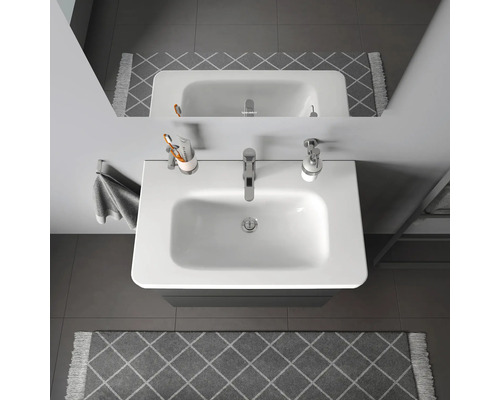 Ansicht von oben auf ein Waschbecken im Badezimmer mit Armatur, Seifenspender, Zahnputzbecher und Handtuch