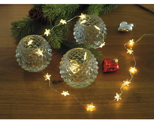 Dekoration mit Sternenlichterkette, Teelichtern und Weihnachtsbaumzweig auf Holztisch