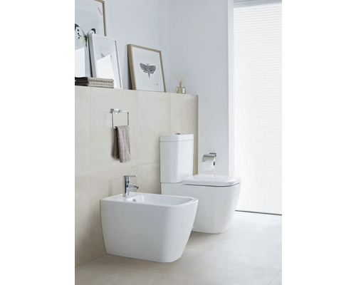 Modernes Badezimmer mit Bidet und Toilette in Weiß, dazu Handtuchhalter und Dekorationen