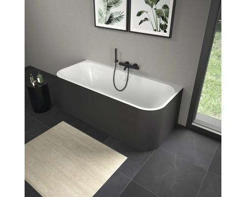 Freistehende Badewanne mit schwarzer Armatur in einem Badezimmer mit Kunstwerken und Teppich.