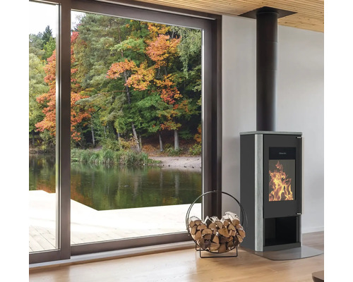 Kaminofen mit Holzkorb in einem hellen Raum mit Blick auf einen See