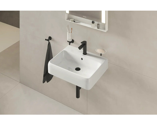 Waschbecken mit Armatur, Handtuch, Seifenschale und beleuchtetem Spiegel im Badezimmer.