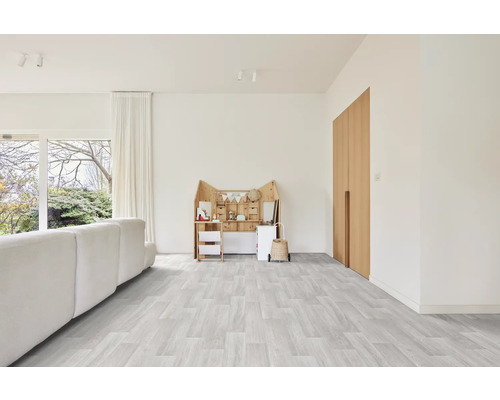 Heller Wohnraum mit Sofa, Spielmöbeln und Holztüren auf hellgrauem Holzboden.