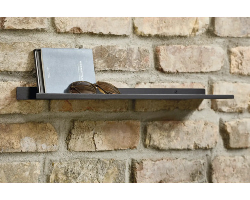 Wandregal mit Buch und Sonnenbrille an einer Ziegelwand