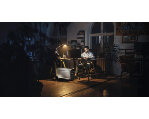 Mann arbeitet am Schreibtisch mit tragbarem Kraftwerk im Raum