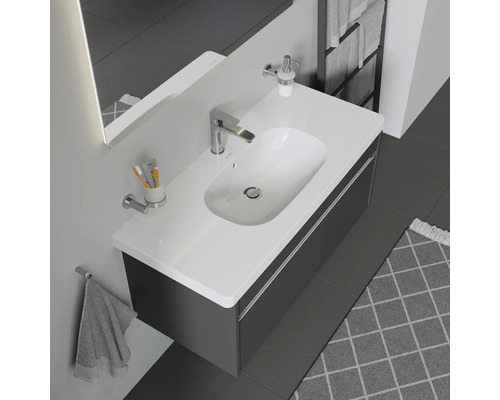 Modernes Badezimmer mit Waschbecken, Unterschrank, Armatur, Seifenspender, Handtuch und weiteren Badaccessoires.