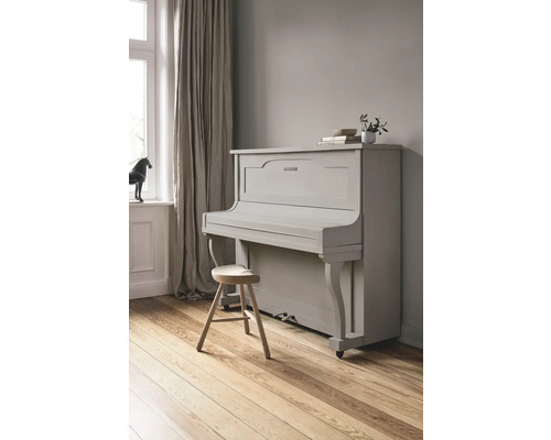 Graues Klavier mit Hocker in einem hellen Raum.