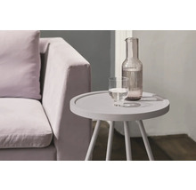 Beistelltisch mit Wasserkanne und Glas neben einem Sofa