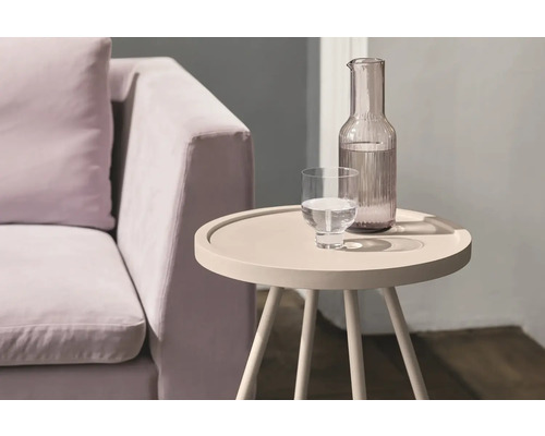 Einrichtungsszene mit Sofa, Wasserglas und Wasserkaraffe auf einem Beistelltisch.