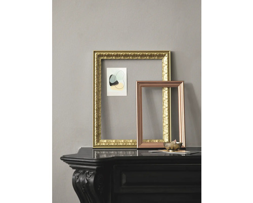 Zwei leere Bilderrahmen in Gold und Kupfer auf einem schwarzen Regal.