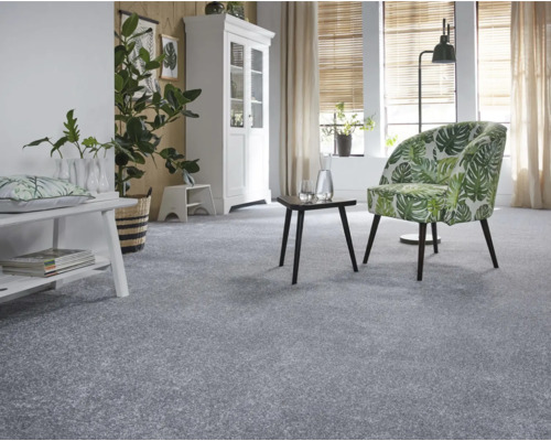 Heller Wohnraum mit Teppichboden, Sessel mit Pflanzenmuster und Dekorationsgegenständen