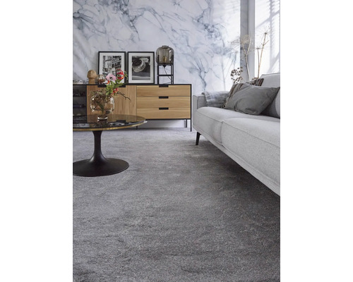 Wohnzimmer mit grauem Teppichboden, Sofa und Sideboard vor einer Marmorwand