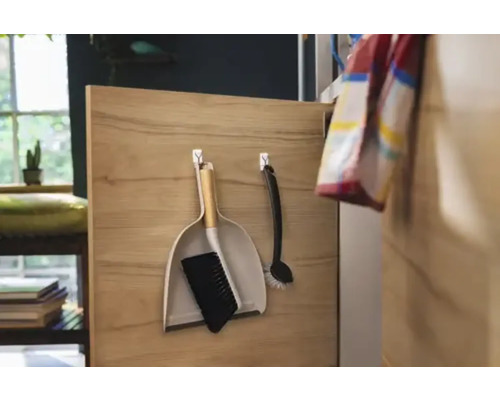 Kehrschaufel und Handfeger hängen an einer Holzplatte