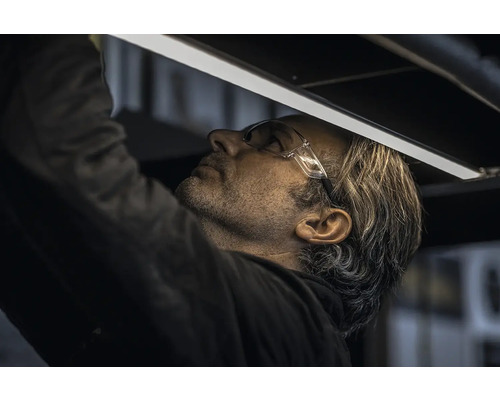 Ein Mann mit Schutzbrille montiert eine LED-Leuchte.