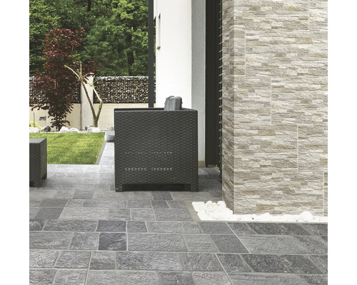 Terrasse mit Pflastersteinen und Wandverkleidung in Steinoptik sowie Sitzmöbeln