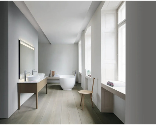 Helles Badezimmer mit Doppelwaschtisch, freistehender Badewanne und Fenster.