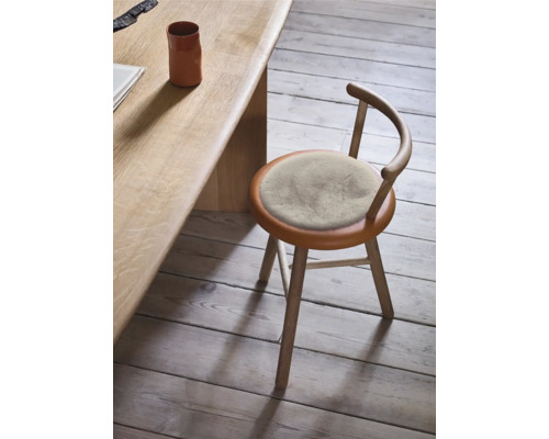 Holzstuhl mit rundem Sitzpolster an einem Holztisch
