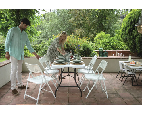 Szene im Garten mit einem Tisch und Stühlen für eine Mahlzeit im Freien.