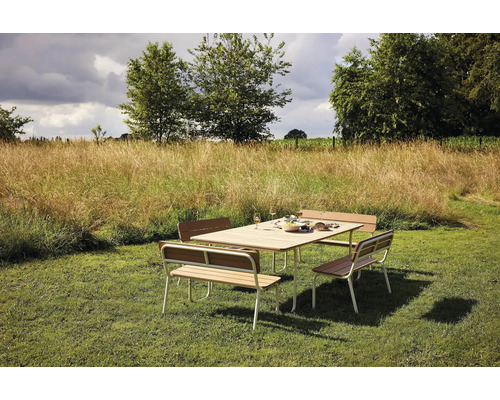 Gartenszene mit Esstisch und Sitzbänken auf einer Rasenfläche.