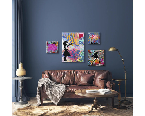 Wohnzimmer mit Ledersofa, Couchtisch, Stehlampe und vier Wandbildern im Graffiti-Stil