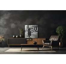 Wohnzimmer mit Kommode, Sessel, Couchtisch, Zimmerpflanze und gerahmtem Schwarzweiß-Foto