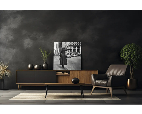 Wohnzimmer mit Kommode, Sessel, Couchtisch, Zimmerpflanze und gerahmtem Schwarzweiß-Foto