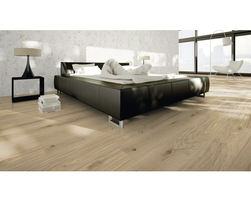 Schlafzimmer mit einem Bett, einem Nachttisch, einer Lampe und einem Holzboden.