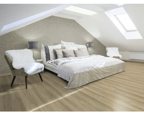 Heller Dachgeschossraum mit Bett, Stühlen und Dachfenstern.