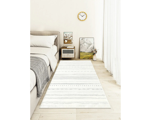 Schlafzimmer mit Bett, Nachttisch und einem Teppich mit Streifenmuster