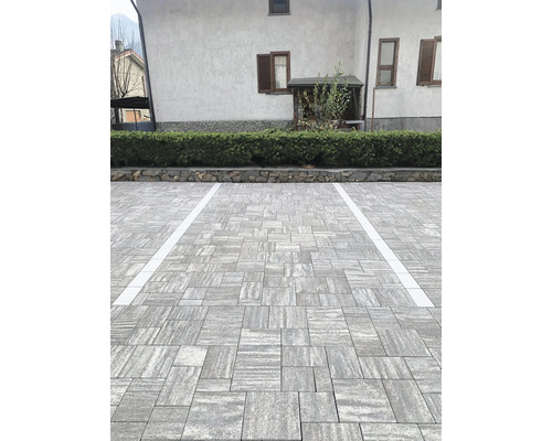 Außenbereich mit Pflastersteinen und Parkplatzmarkierungen vor einem Gebäude