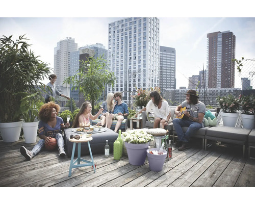 Gesellschaft sitzt auf einer Dachterrasse mit Gartenmöbeln vor einer Stadtkulisse