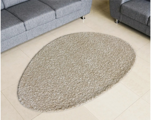 Ovaler Teppich vor Sofa auf Fliesenboden