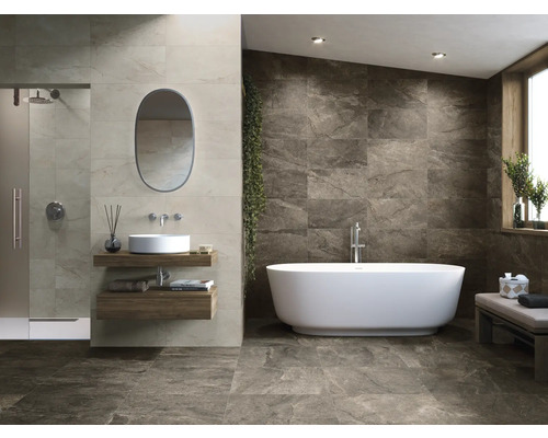 Badezimmer mit Dusche, Waschbecken, Spiegel und freistehender Badewanne vor einer gefliesten Wand.