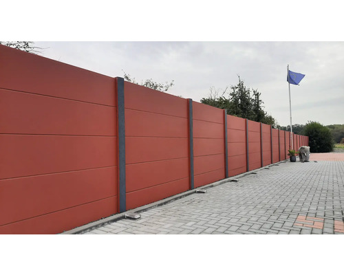 Lange Betonzaun mit grauen Säulen und Pflastersteinen