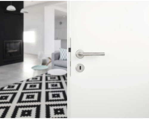 Geöffnete weiße Tür mit Edelstahlgriff zu einem Wohnzimmer mit Teppich