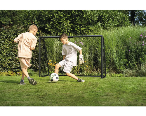 Zwei Jungen spielen Fußball vor einem Fußballtor im Garten.